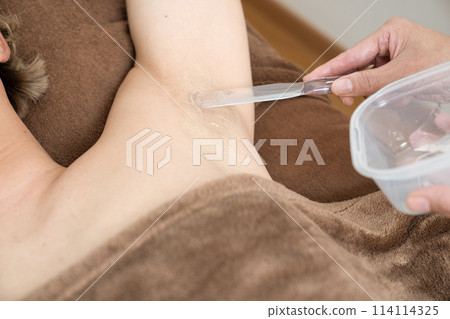 一名女性將凝膠塗抹在接受除毛治療的男性身上的手 一名女性將凝膠塗抹在接受除毛治療的男性身上的手 114114325