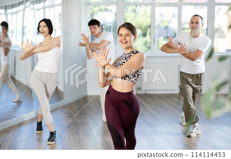 Young girl and group of positive people practicing energetic lindy hop movements at dance school 114114453