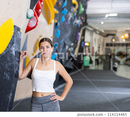 Motivated girl standing by bouldering wall in climbing center 114114465