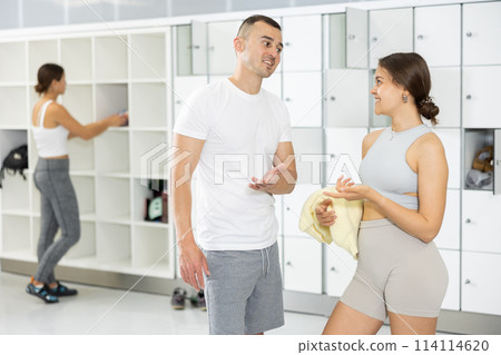 Positive man chatting with female friend in climbing gym locker room 114114620