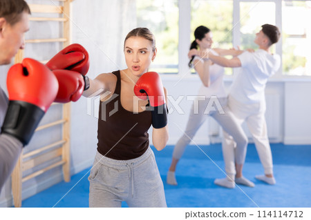 Young girl training boxing with partner during sports classes Young girl training boxing with partner during sports classes 114114712