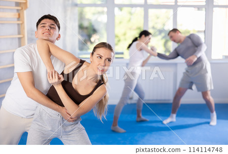 Young girl practicing self-defense techniques in pairs with guy Young girl practicing self-defense techniques in pairs with guy 114114748