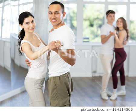 Young couple enjoying slow foxtrot in dance studio 114114806