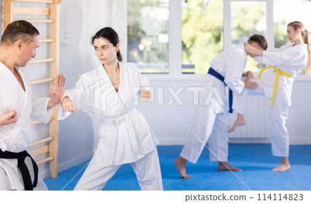 Karate training - man and woman in kimono sparring in gym 114114823