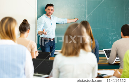 Male teacher giving presentation for students in lecture hall Male teacher giving presentation for students in lecture hall 114114832