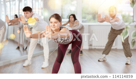 Group of women and men enjoying active dance movement in modern studio 114114859