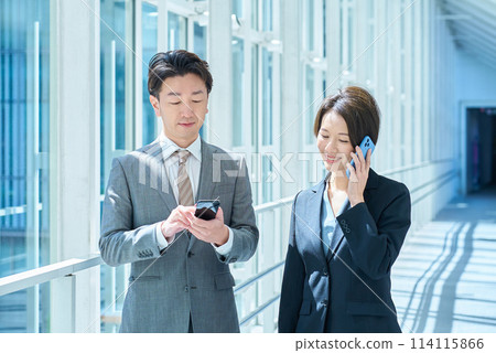 穿著西裝的男女操作智慧型手機 114115866