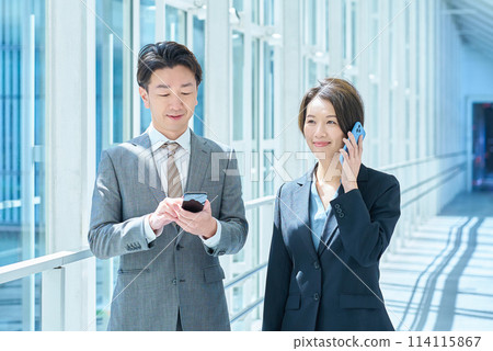 穿著西裝的男女操作智慧型手機 114115867