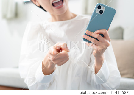 A woman angry with a smartphone A woman angry with a smartphone 114115873