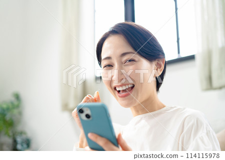 拿著智慧型手機的微笑的女人 114115978