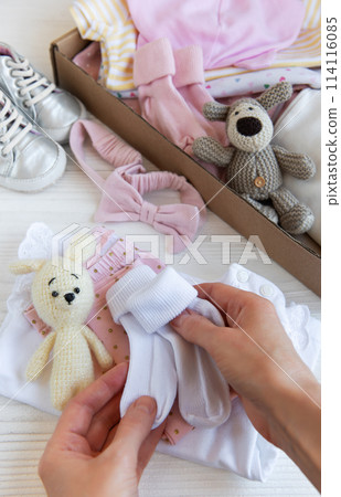 Women's hands collect children's clothes into boxes. 114116085