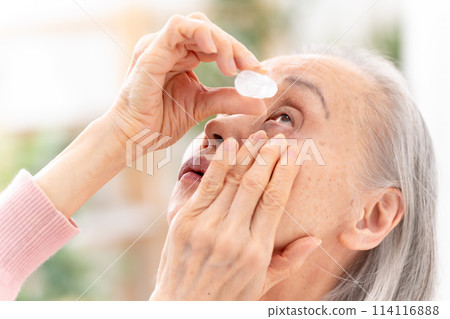 Senior woman pointing eye drops Senior woman pointing eye drops 114116888