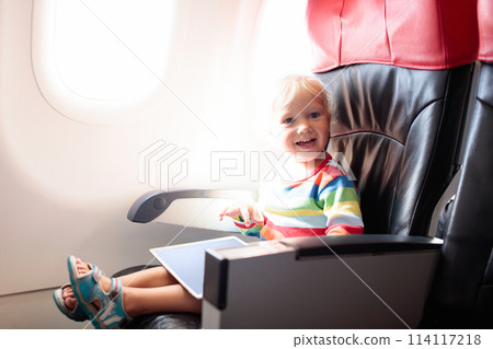 Child in airplane with tablet computer. Child in airplane with tablet computer. 114117218