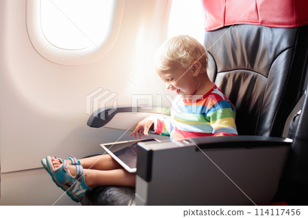Child in airplane with tablet computer. 114117456