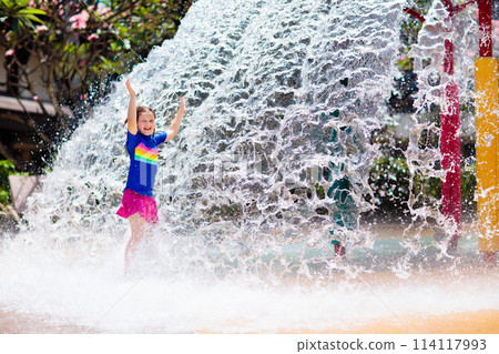 Child playing under tip bucket in water park. 114117993