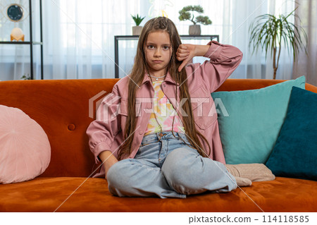 Upset girl child showing thumbs down sign dislike gesture expressing discontent disapproval feedback 114118585