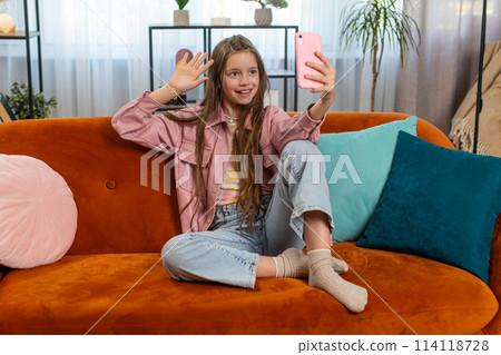 Happy child girl blogger taking selfie on smartphone communicating video call with subscribers Happy child girl blogger taking selfie on smartphone communicating video call with subscribers 114118728