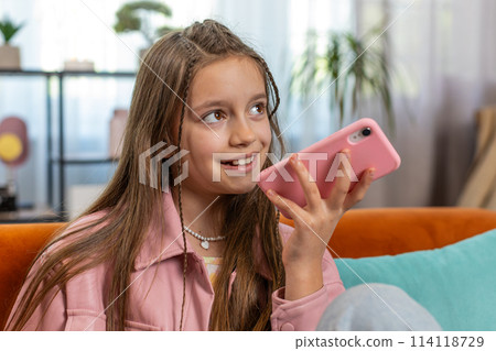 Happy girl child making online phone call conversation loudspeaker talking with friends at home Happy girl child making online phone call conversation loudspeaker talking with friends at home 114118729