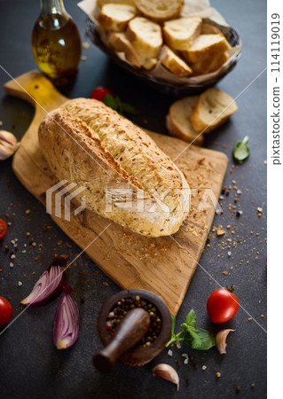 freshly baked bread on wooden cutting board on dark table freshly baked bread on wooden cutting board on dark table 114119019