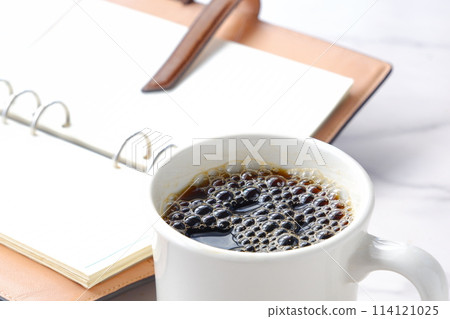 An image of someone drinking coffee, opening their ring-type system organizer, and thinking about how to organize their work An image of someone drinking coffee, opening their ring-type system organizer, and thinking about how to organize their work 114121025