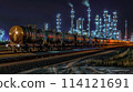 A freight train with tank wagons drives slowly through an industrial area with chemical factory. 114121691