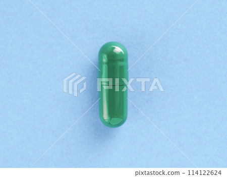 Green two-piece hard starch capsule on blue background with copy space. Medical and Health concept. 114122624