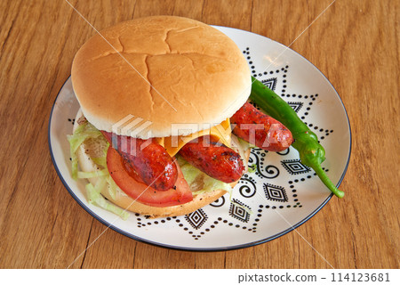 Merguez burger on decorated plate on wooden textured table 114123681