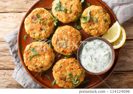 Chickpea Fritters with garlic, fresh herbs, spices served with dipping yogurt sauce close-up in plate. Horizontal top view 114124096