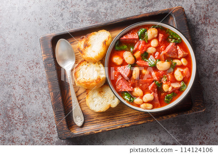 Spicy stew of lima beans, chorizo and spinach in tomato sauce close-up in a bowl. Horizontal top view Spicy stew of lima beans, chorizo and spinach in tomato sauce close-up in a bowl. Horizontal top view 114124106