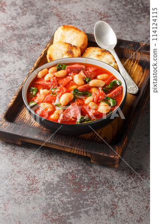 Slow cooked stew of butter beans, chorizo and spinach in tomato sauce close-up in a bowl. Vertical Slow cooked stew of butter beans, chorizo and spinach in tomato sauce close-up in a bowl. Vertical 114124115