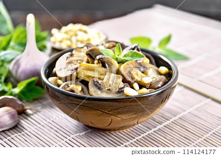 Champignons with oregano and nuts in bowl on dark board Champignons with oregano and nuts in bowl on dark board 114124177