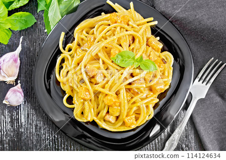 Spaghetti with pumpkin and bacon in plate on dark board top Spaghetti with pumpkin and bacon in plate on dark board top 114124634