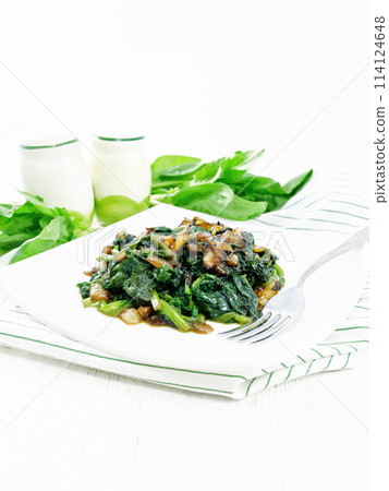 Spinach fried with onions in plate on towel 114124648