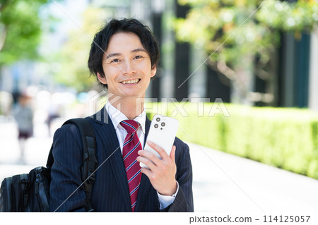 A businessman in a suit holding a smartphone 114125057