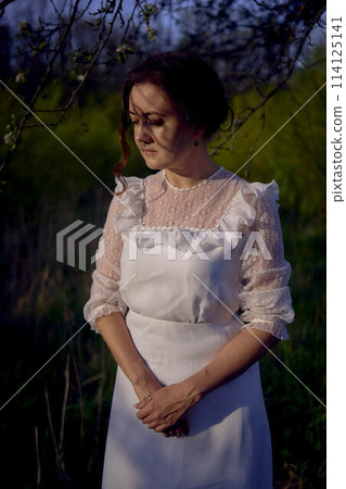 beautiful woman in white vintage dress with train in spring garden at sunset beautiful woman in white vintage dress with train in spring garden at sunset 114125141