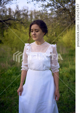 beautiful woman in white vintage dress with train in spring garden at sunset beautiful woman in white vintage dress with train in spring garden at sunset 114125147