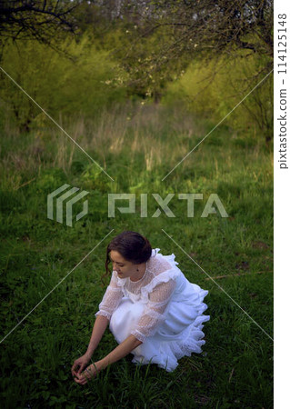 beautiful woman in white vintage dress with train in spring garden at sunset beautiful woman in white vintage dress with train in spring garden at sunset 114125148