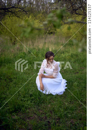 beautiful woman in white vintage dress with train in spring garden at sunset beautiful woman in white vintage dress with train in spring garden at sunset 114125157