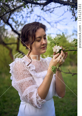 beautiful woman in white vintage dress with train in spring garden at sunset beautiful woman in white vintage dress with train in spring garden at sunset 114125181