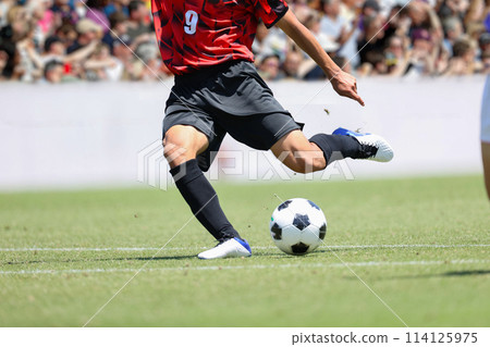 A player kicking the ball in a soccer match A player kicking the ball in a soccer match 114125975