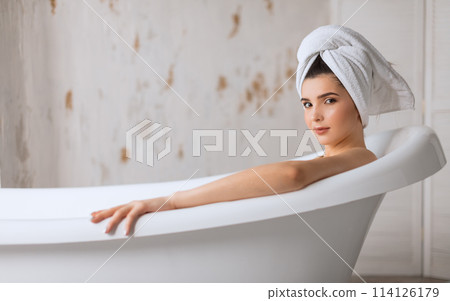 Relaxed young woman laying in bathtub Relaxed young woman laying in bathtub 114126179