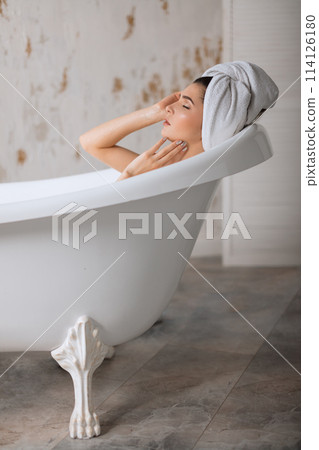 Relaxed young woman laying in bathtub Relaxed young woman laying in bathtub 114126180