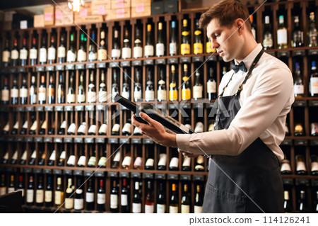 Sommelier offering bottle of red wine to customer 114126241