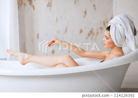 Relaxed young woman laying in bathtub 114126392