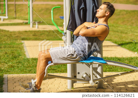 Man doing abs exercises in outdoor gym Man doing abs exercises in outdoor gym 114126621
