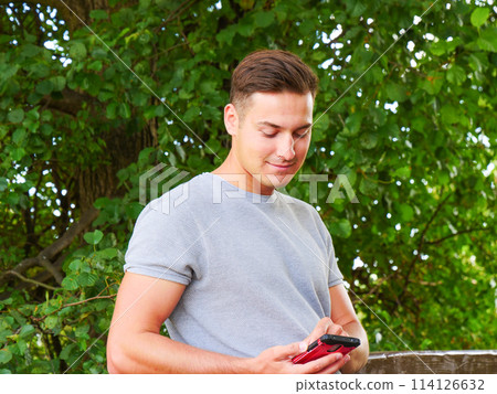 Man using mobile phone in park Man using mobile phone in park 114126632