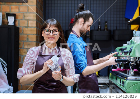 Teamwork, man and woman in aprons working together at bar counter in coffee shop cafe Teamwork, man and woman in aprons working together at bar counter in coffee shop cafe 114126829