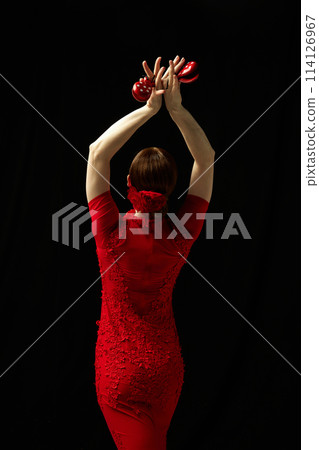 Moment frozen in time. Elegant woman in red dress standing with castanets against black background Moment frozen in time. Elegant woman in red dress standing with castanets against black background 114126967