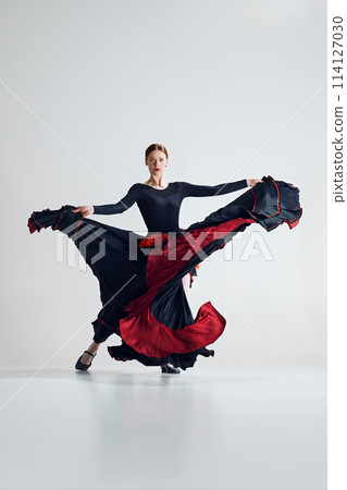 Passionate essence of flamenco dance. Artistic woman performing dynamic pose dancing against grey studio background 114127030