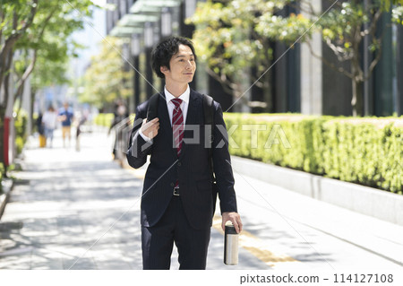 A businessman in his 30s walking through an office district 114127108